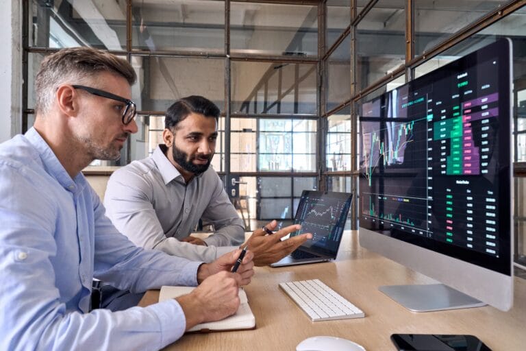 Two people looking at computer screen with graphs