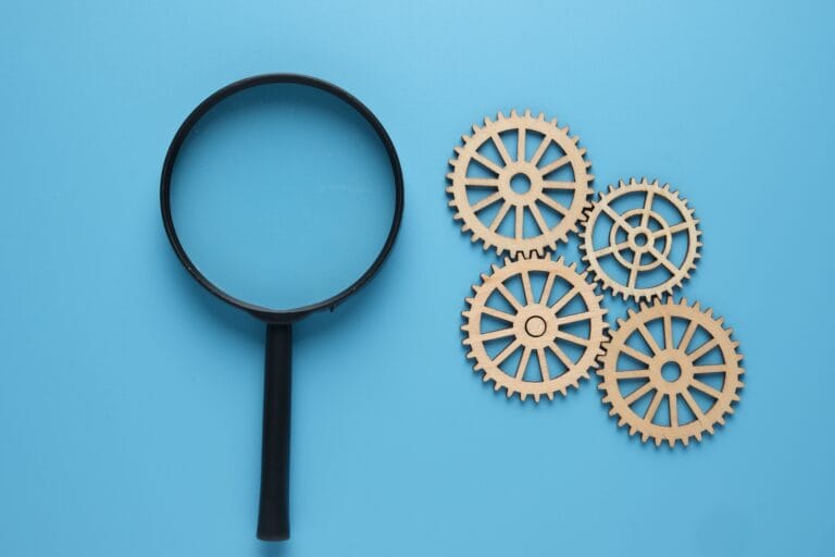 A magnifying glass with gear on blue background.