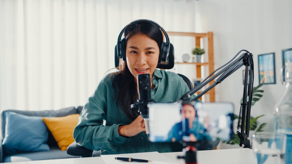 Influencer at desk with headphones and microphone for recording.