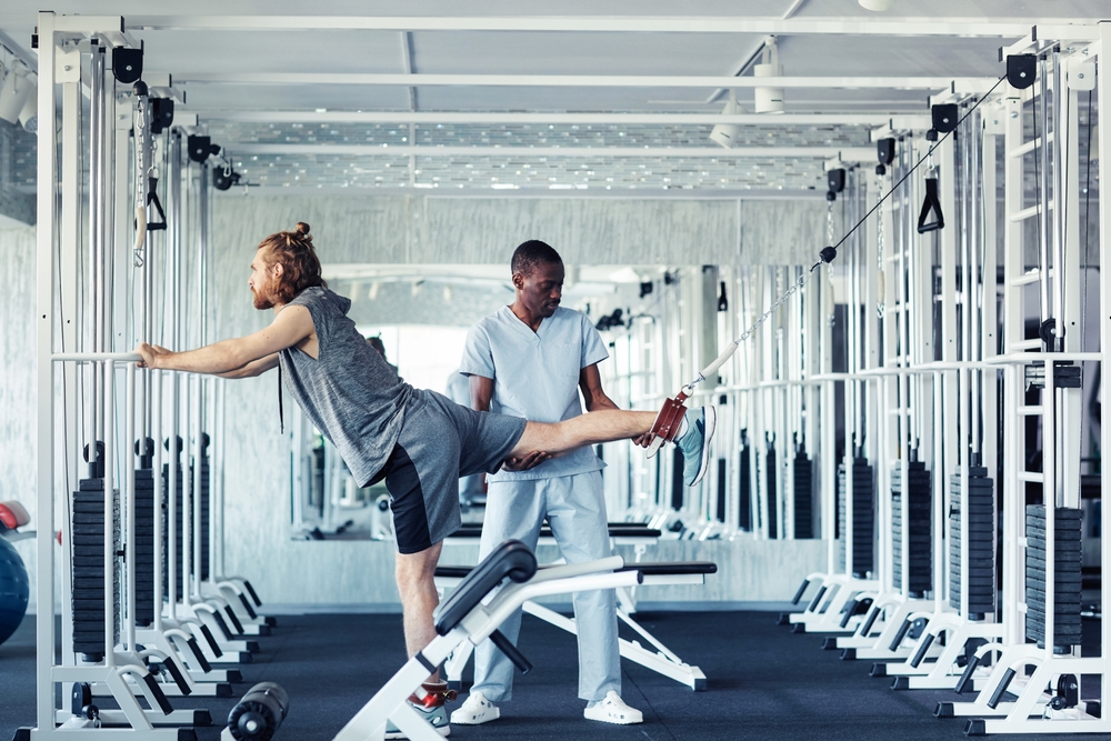 African,Young,Therapist,Training,Patient,With,Injury,Leg,Using,Special