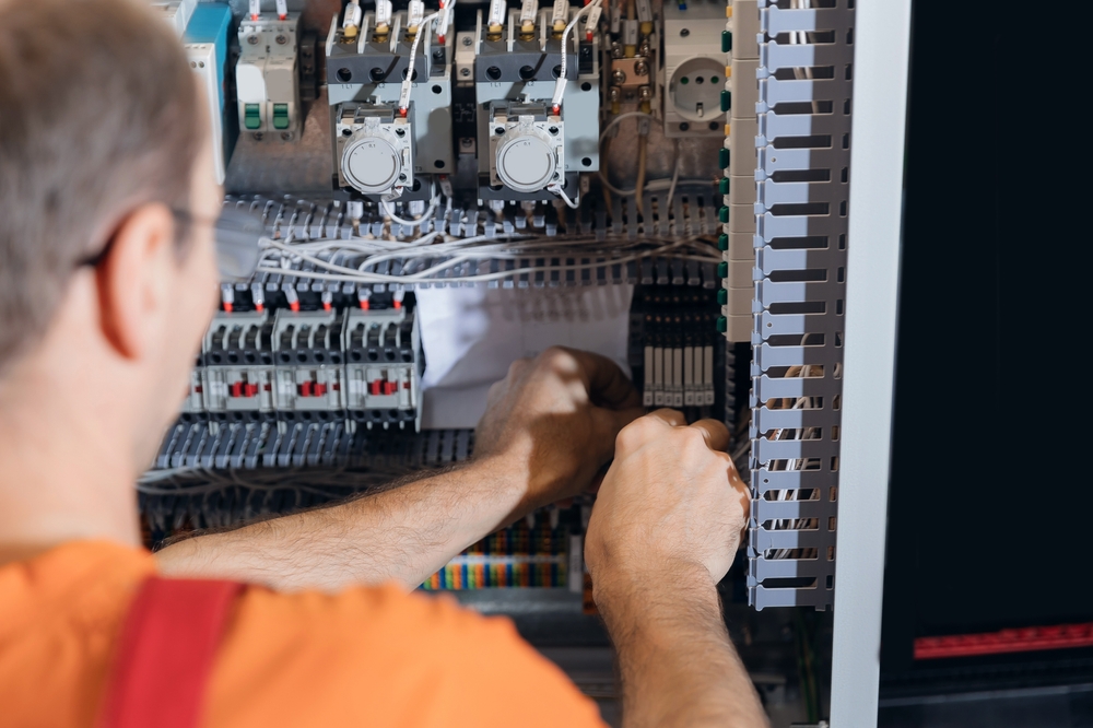 Back,View,Worker,Technician,Adjusting,Industrial,Control,Panel,In,Factory.